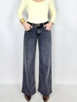 Jeans in grintoso color grigio slavato. Borchie applicate sulle rifiniture. Modello a palazzo.