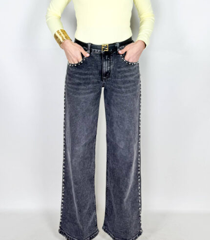 Jeans in grintoso color grigio slavato. Borchie applicate sulle rifiniture. Modello a palazzo.