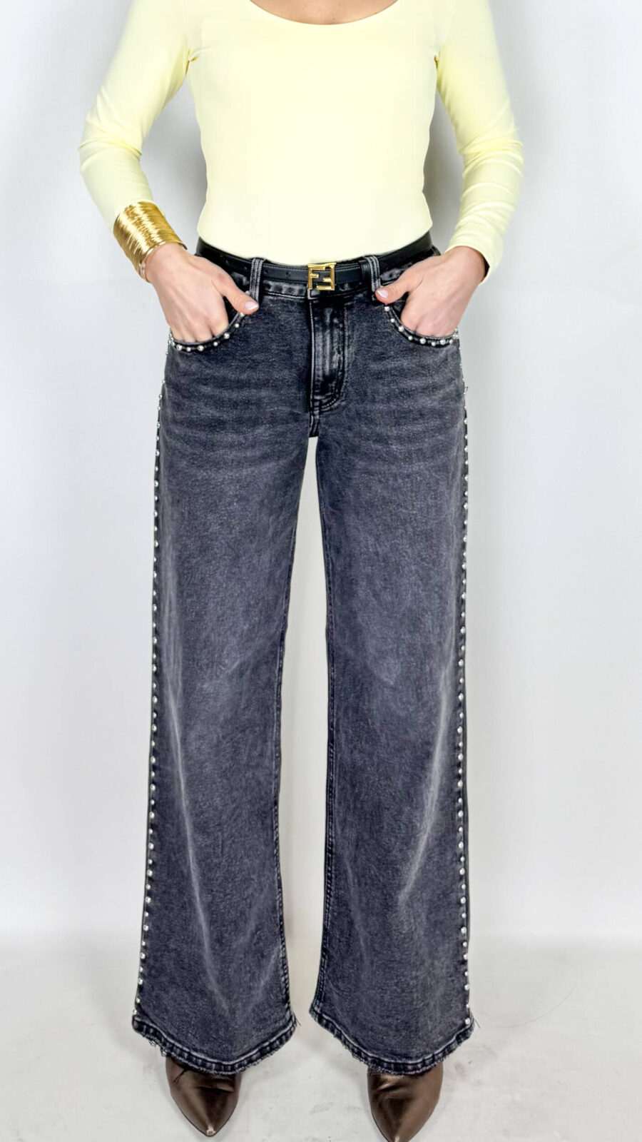 Jeans in grintoso color grigio slavato. Borchie applicate sulle rifiniture. Modello a palazzo.