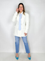 Blazer doppiopetto bianco dal design elegante e sofisticato, pensato per un look deciso e contemporaneo. Il collo a revers e la chiusura frontale a doppio petto conferiscono struttura e carattere al capo, mentre le spalline imbottite valorizzano la silhouette con un tocco di autorità e stile. La linea lunga fino alla coscia e la vita segnata creano un effetto slanciato e femminile, perfetto da abbinare a pantaloni, gonne o jeans per outfit dal fascino raffinato e moderno