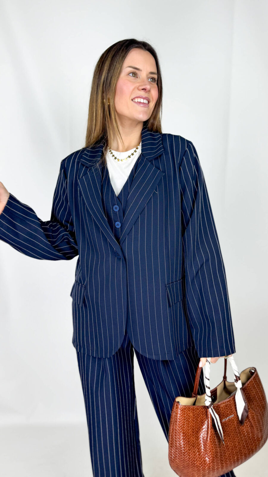 Una giacca gessata dal taglio oversize, dallo stile deciso e contemporaneo. La silhouette è ampia e strutturata, con spalle leggermente pronunciate e linea morbida che cade dritta lungo il busto. Il motivo gessato, con sottili righe verticali, richiama l’eleganza sartoriale classica, reinterpretata in chiave moderna. Presenta chiusura frontale con bottone, rever puliti e tasche a filetto