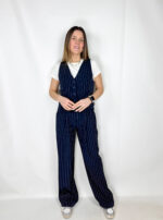 La linea scende ampia e fluida lungo la gamba, creando un effetto slanciato ed elegante. Il motivo gessato, con righe sottili verticali, dona raffinatezza e richiama l’estetica tailoring classica.