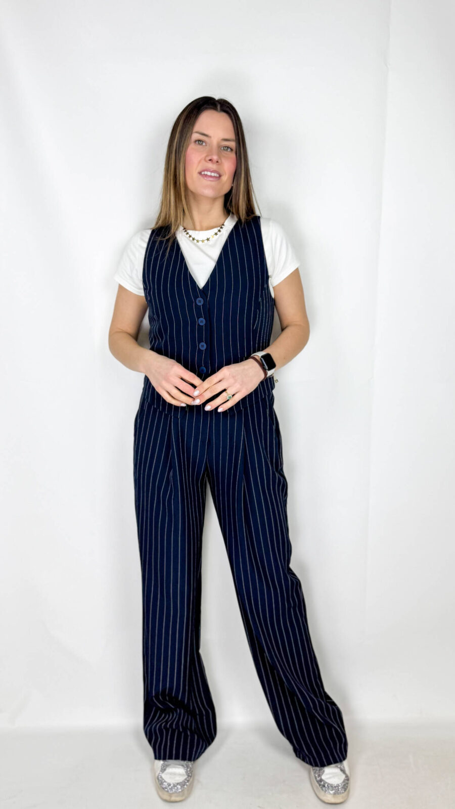 La linea scende ampia e fluida lungo la gamba, creando un effetto slanciato ed elegante. Il motivo gessato, con righe sottili verticali, dona raffinatezza e richiama l’estetica tailoring classica.