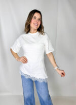 Maglia bianca moderna svasata con balza in pizzo.