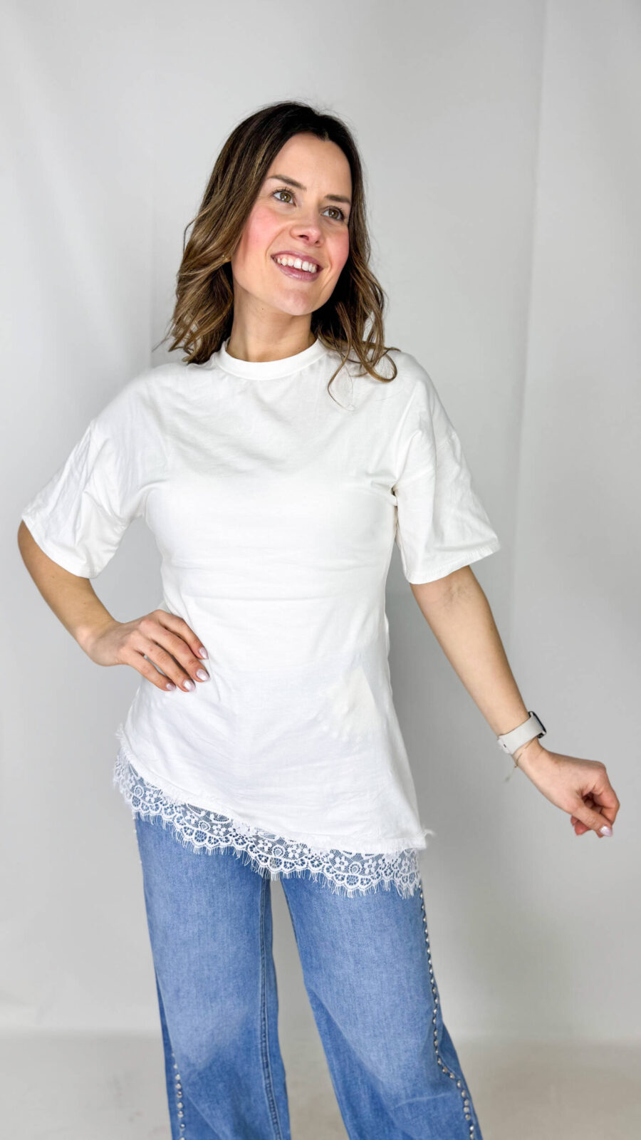 Maglia bianca moderna svasata con balza in pizzo.