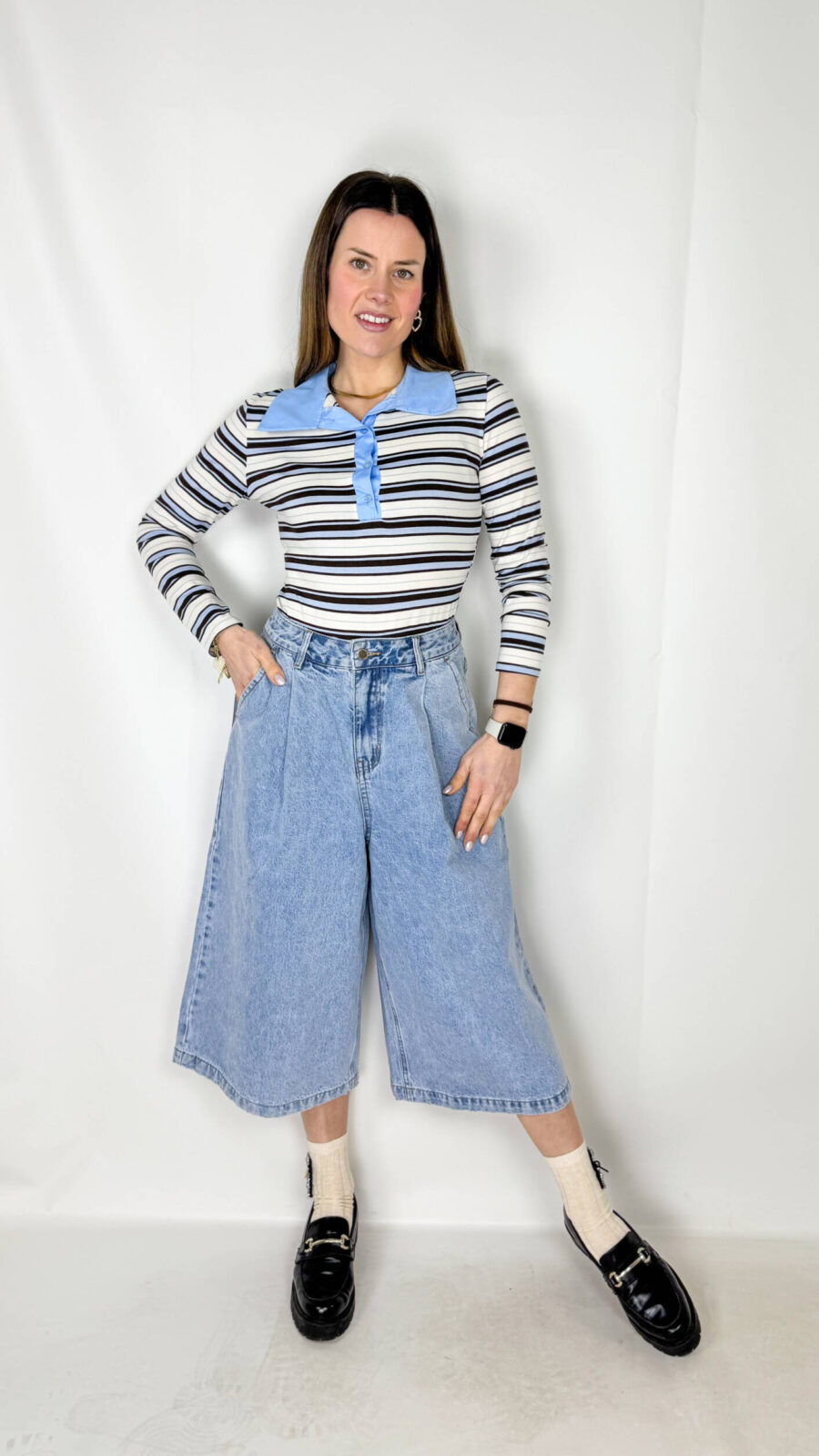 Jeans modello bermuda a gamba ampia, lunghi fino al polpaccio, dal colore azzurro chiaro fresco e versatile. Il design è arricchito da pence in vita, che donano struttura e un tocco sartoriale al capo, valorizzando la silhouette senza rinunciare al comfort.