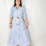 Abito lungo femminile e raffinato, realizzato in cotone leggero con righe azzurre e bianche, ideale per creare un look fresco e chic. Il modello chemisier con maniche 3/4 dona eleganza e versatilità, perfetto per le giornate più calde o per eventi casual-eleganti. I ricami delicati aggiungono un tocco artigianale e sofisticato, mentre la cintura in vita permette di valorizzare la silhouette creando una linea armoniosa e femminile.