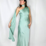 Abito lungo in satin color verde acqua delicato, raffinato e luminoso. Il modello monospalla dona un tocco sofisticato e moderno, mentre il morbido strascico può essere avvolto intorno al collo creando un elegante effetto drappeggiato. Il tessuto satinato scivola delicatamente lungo la silhouette, seguendo le linee del corpo con naturalezza e leggerezza. Perfetto per cerimonie, serate eleganti ed eventi speciali