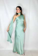 Abito lungo in satin color verde acqua delicato, raffinato e luminoso. Il modello monospalla dona un tocco sofisticato e moderno, mentre il morbido strascico può essere avvolto intorno al collo creando un elegante effetto drappeggiato. Il tessuto satinato scivola delicatamente lungo la silhouette, seguendo le linee del corpo con naturalezza e leggerezza. Perfetto per cerimonie, serate eleganti ed eventi speciali