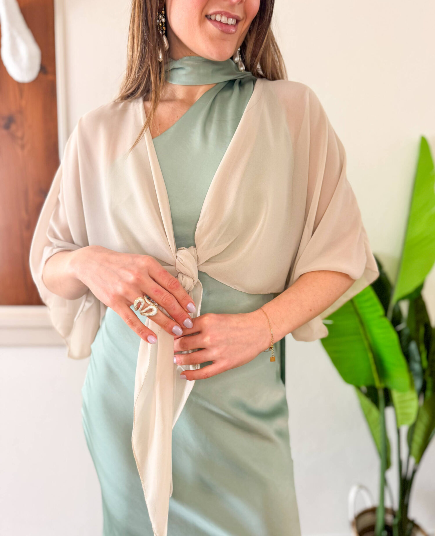 Coprispalle elegante in tessuto leggero e velato, perfetto per completare abiti da cerimonia con un tocco di raffinatezza. Il modello si allaccia delicatamente sul petto, creando un effetto morbido e femminile. Le maniche corte ampie donano movimento e leggerezza, rendendolo ideale da indossare sopra abiti eleganti durante cerimonie ed eventi speciali.