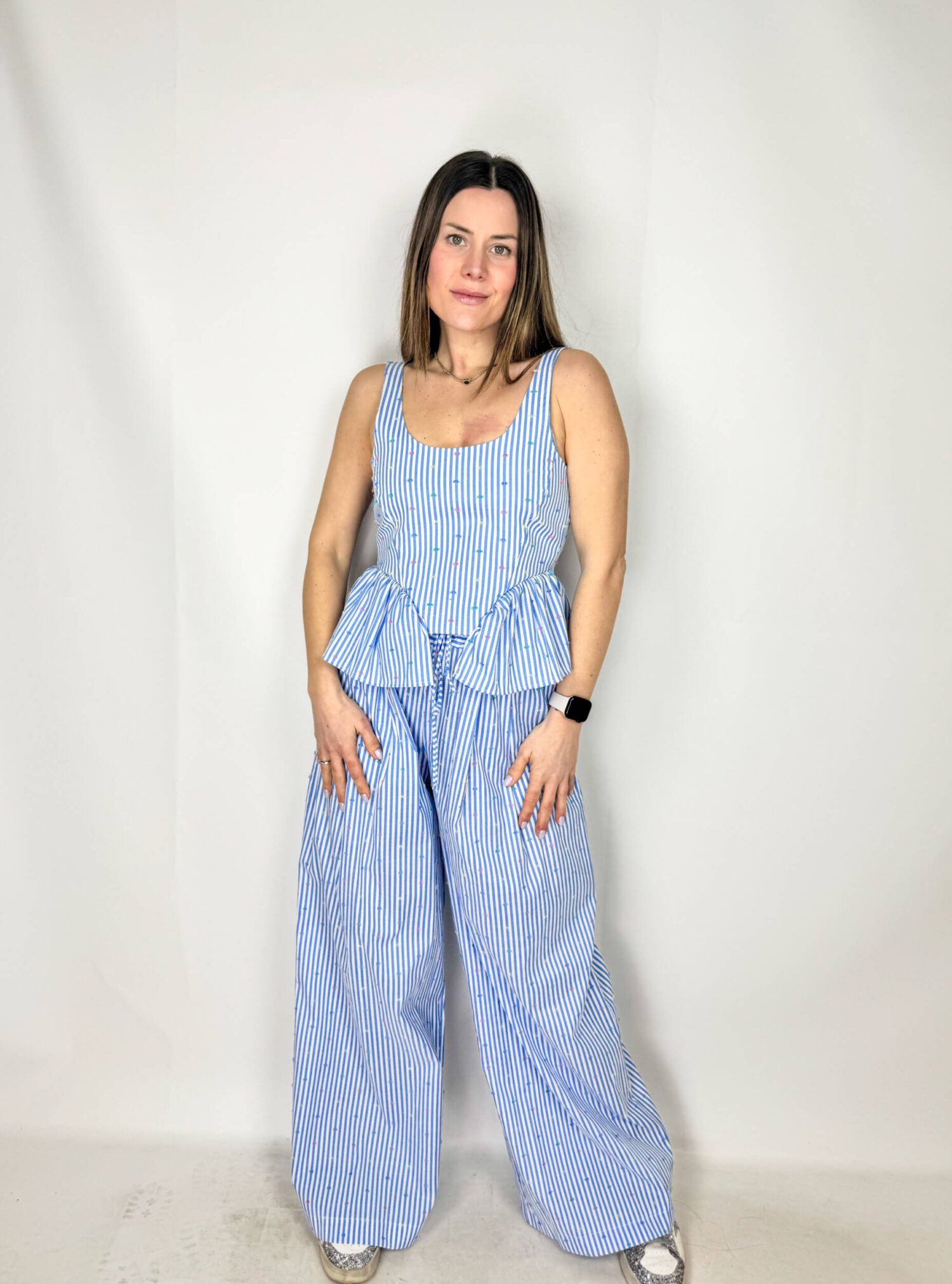 Coordinato Mia fresco e sofisticato, composto da pantaloni a palazzo e top crop coordinato. I pantaloni, ampi e fluidi, scendono morbidi lungo la gamba