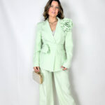 Completo elegante dal taglio contemporaneo, pensato per unire raffinatezza e comfort. Il pantalone sartoriale presenta pence frontali che valorizzano la linea, mentre l’elastico sul retro della vita garantisce una vestibilità pratica e confortevole. Chiusura con bottone e zip per una finitura pulita e curata. La giacca doppiopetto completa il look con un’allure sofisticata: arricchita da una spilla a forma di rosa amovibile, aggiunge un dettaglio distintivo e femminile. La cintura/collarino in coordinato definisce la silhouette e permette di personalizzare lo styling,