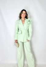 Completo elegante dal taglio contemporaneo, pensato per unire raffinatezza e comfort. Il pantalone sartoriale presenta pence frontali che valorizzano la linea, mentre l’elastico sul retro della vita garantisce una vestibilità pratica e confortevole. Chiusura con bottone e zip per una finitura pulita e curata. La giacca doppiopetto completa il look con un’allure sofisticata: arricchita da una spilla a forma di rosa amovibile, aggiunge un dettaglio distintivo e femminile. La cintura/collarino in coordinato definisce la silhouette e permette di personalizzare lo styling,