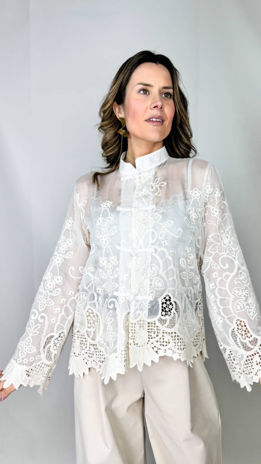 Camicia Japan elegante realizzata con un tessuto semi-trasparente, impreziosita dal ricamo floreale. Il collo alto leggermente strutturato aggiunge un tocco sofisticato mentre le maniche ampie terminano con polsini lavorati in pizzo.