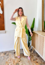 Coordinato dal carattere deciso e contemporaneo, pensato per chi ama distinguersi con eleganza. Il gilet doppiopetto è il protagonista assoluto: strutturato, con una linea sartoriale impeccabile, è impreziosito da bottoni dorati che decorano sia la chiusura frontale sia le spalline, aggiungendo un tocco sofisticato e distintivo. La cintura regolabile in vita valorizza la silhouette, permettendo una vestibilità personalizzata e femminile. Il pantalone a gamba larga completa il look con un’attitudine moderna e fluida. Caratterizzato da una doppia chiusura frontale, riprende il design dei modelli più iconici e di tendenza del 2026, offrendo una struttura pulita e un fit impeccabile.