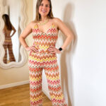 Tuta elasticizzata multicolore dallo stile vibrante e contemporaneo, ispirata alle iconiche fantasie zig-zag. Il design avvolgente valorizza la silhouette grazie al tessuto stretch che si adatta perfettamente al corpo, garantendo comfort e libertà di movimento. Il top a triangolo dona un’allure femminile e sensuale, mentre la schiena semi scoperta aggiunge un tocco audace e sofisticato, lasciando intravedere la pelle con eleganza. Il pantalone a gamba dritta completa il look con una linea fluida e slanciata, bilanciando perfettamente il fit aderente della parte superiore.