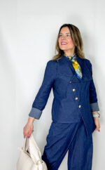 Coordinato in leggero denim primaverile, fresco e contemporaneo, ideale per la mezza stagione. Il pantalone, con elastico in vita, presenta una linea morbida a ovetto che avvolge la silhouette con comfort e stile. La giacca, dal design originale, si chiude frontalmente in modo trasversale ed è impreziosita da bottoni dorati che aggiungono un tocco luminoso e sofisticato. Un completo moderno e ricercato, perfetto per look casual-chic dal carattere distintivo.