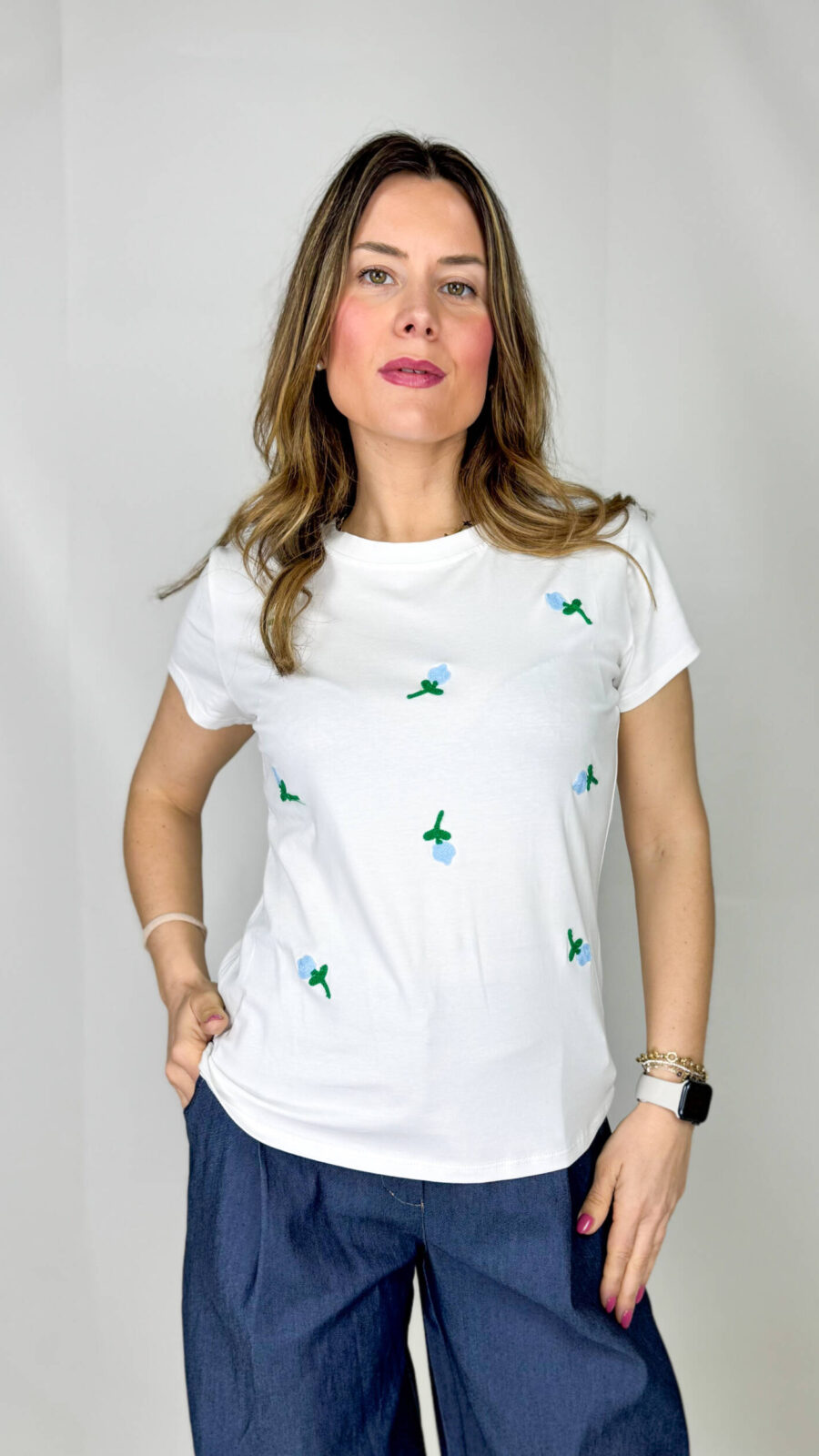 T-shirt in morbido cotone, leggera e confortevole, perfetta per la stagione primaverile ed estiva. Il design è impreziosito da delicati fiorellini applicati sul davanti, nelle tonalità fresche dell’azzurro e del verde, che donano un tocco romantico e naturale al capo