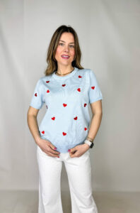 Pullover girocollo in 100% viscosa, leggero e morbido al tatto, ideale per un comfort quotidiano con un tocco femminile. Il modello a manica corta è impreziosito da delicati cuori rossi ricamati, che aggiungono un dettaglio romantico e vivace al capo. La lavorazione a costine sul fondo garantisce una vestibilità stabile e leggermente aderente