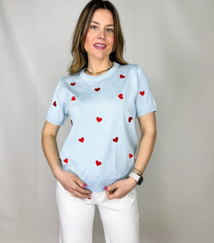Pullover girocollo in 100% viscosa, leggero e morbido al tatto, ideale per un comfort quotidiano con un tocco femminile. Il modello a manica corta è impreziosito da delicati cuori rossi ricamati, che aggiungono un dettaglio romantico e vivace al capo. La lavorazione a costine sul fondo garantisce una vestibilità stabile e leggermente aderente