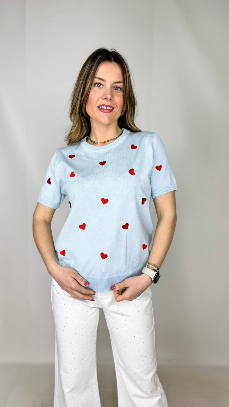 Pullover girocollo in 100% viscosa, leggero e morbido al tatto, ideale per un comfort quotidiano con un tocco femminile. Il modello a manica corta è impreziosito da delicati cuori rossi ricamati, che aggiungono un dettaglio romantico e vivace al capo. La lavorazione a costine sul fondo garantisce una vestibilità stabile e leggermente aderente