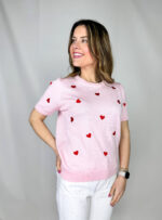 Pullover girocollo in 100% viscosa, leggero e morbido al tatto, ideale per un comfort quotidiano con un tocco femminile. Il modello a manica corta è impreziosito da delicati cuori rossi ricamati, che aggiungono un dettaglio romantico e vivace al capo. La lavorazione a costine sul fondo garantisce una vestibilità stabile e leggermente aderente
