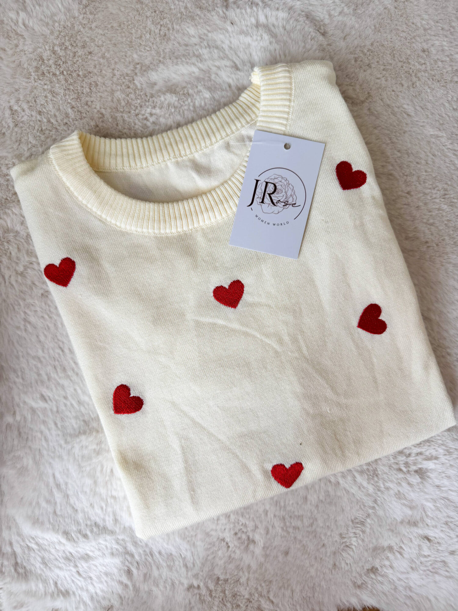 Pullover girocollo in 100% viscosa, leggero e morbido al tatto, ideale per un comfort quotidiano con un tocco femminile. Il modello a manica corta è impreziosito da delicati cuori rossi ricamati, che aggiungono un dettaglio romantico e vivace al capo. La lavorazione a costine sul fondo garantisce una vestibilità stabile e leggermente aderente