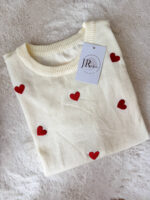 Pullover girocollo in 100% viscosa, leggero e morbido al tatto, ideale per un comfort quotidiano con un tocco femminile. Il modello a manica corta è impreziosito da delicati cuori rossi ricamati, che aggiungono un dettaglio romantico e vivace al capo. La lavorazione a costine sul fondo garantisce una vestibilità stabile e leggermente aderente