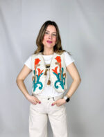 Gilet in 100% cotone, interamente realizzato a mano, espressione di artigianalità e cura per i dettagli. La superficie è arricchita da ricami colorati che donano vivacità e unicità al capo, rendendolo un vero pezzo distintivo. La chiusura con asola sul petto aggiunge un tocco delicato e funzionale