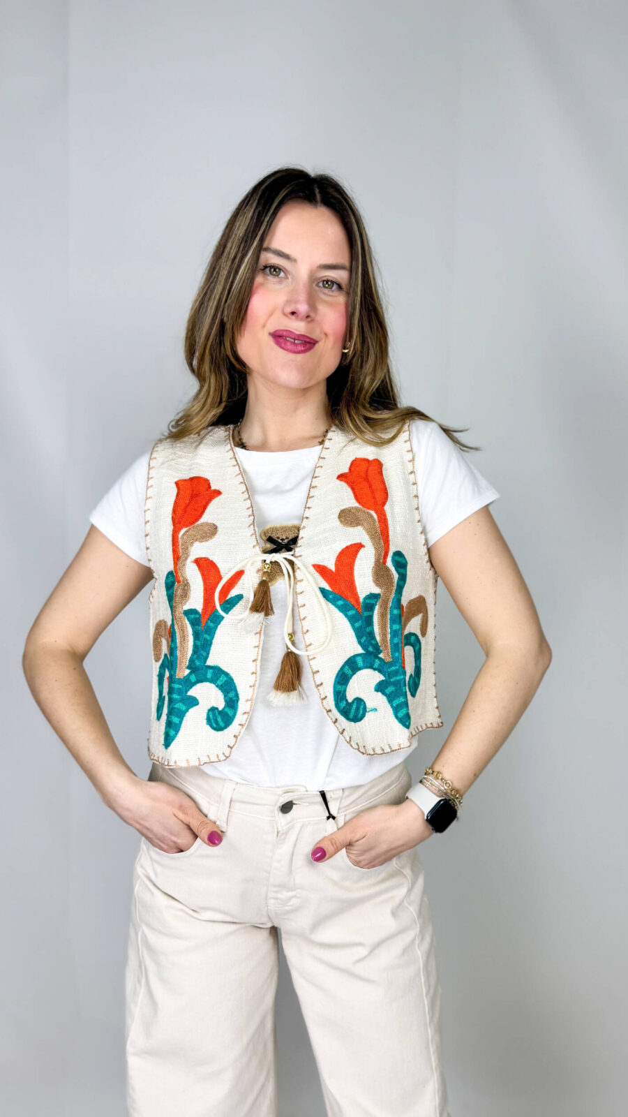 Gilet in 100% cotone, interamente realizzato a mano, espressione di artigianalità e cura per i dettagli. La superficie è arricchita da ricami colorati che donano vivacità e unicità al capo, rendendolo un vero pezzo distintivo. La chiusura con asola sul petto aggiunge un tocco delicato e funzionale