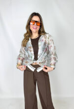 Camicia velata dalla delicata fantasia a fiorellini, leggera e femminile, perfetta per la stagione primaverile. Il tessuto impalpabile accarezza la silhouette, mentre le maniche 3/4 morbide donano movimento e comfort. Versatile e di tendenza, può essere indossata annodata in vita per un look fresco e dinamico, oppure lasciata morbida per un effetto più romantico e rilassato.