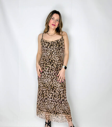 Abito lungo in fantasia leopardata, realizzato in tessuto elasticizzato che avvolge la silhouette esaltandone le forme con naturale eleganza. Il modello presenta uno scollo a barchetta raffinato, che valorizza le spalle, mentre la schiena leggermente scoperta aggiunge un tocco sensuale e sofisticato. La lunghezza alla caviglia slancia la figura, rendendo il capo ideale sia per il giorno che per la sera.