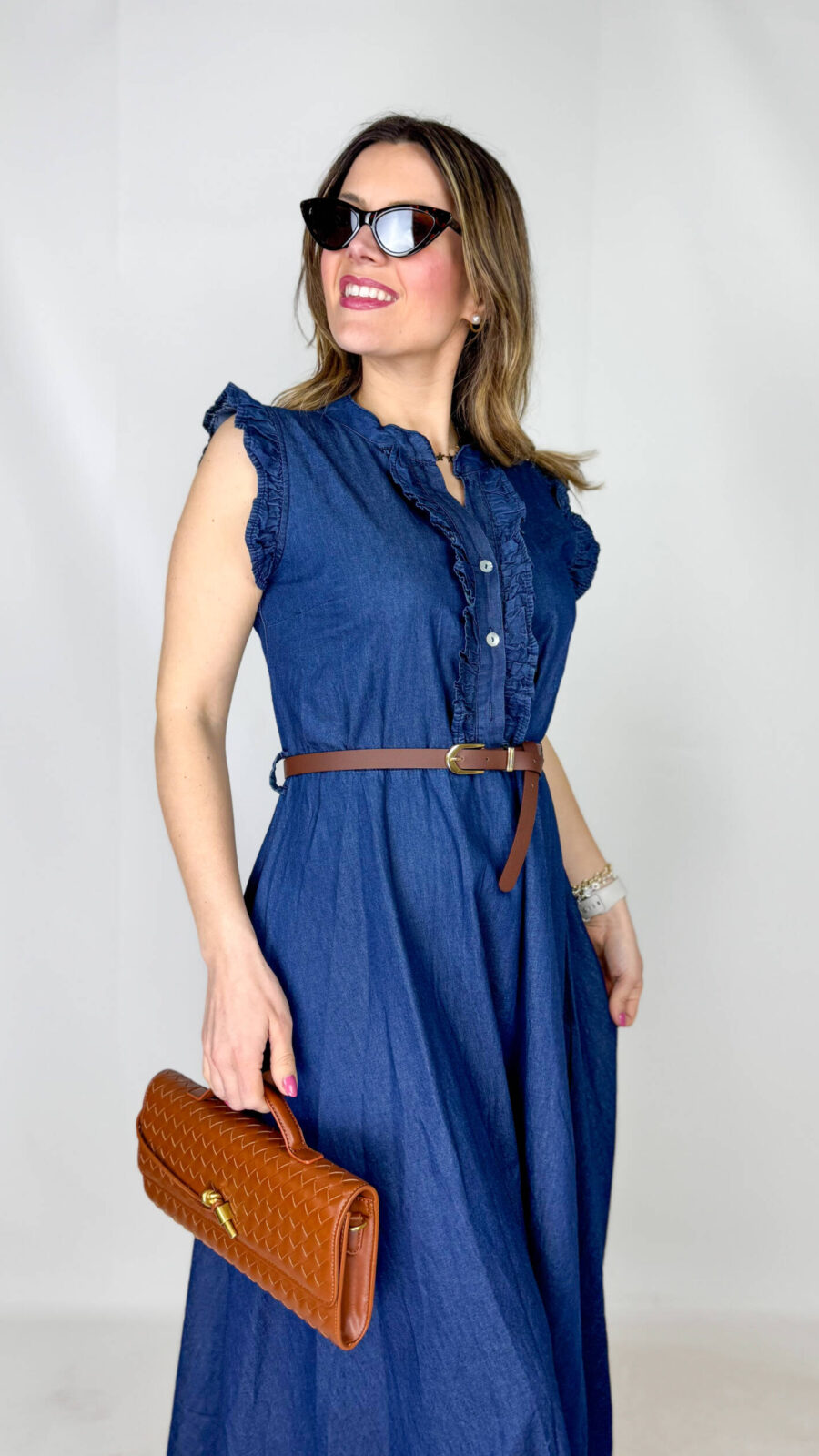 Abito in 100% denim di cotone, dal carattere fresco e contemporaneo, perfetto per uno stile casual-chic. Il top smanicato presenta un elegante collo alla coreana e un delicato rouge sul petto che aggiunge volume e femminilità al design. La gonna morbida scende fluida, donando movimento e comfort alla silhouette. In vita, la cintura regolabile marrone sottolinea il punto vita e completa il look