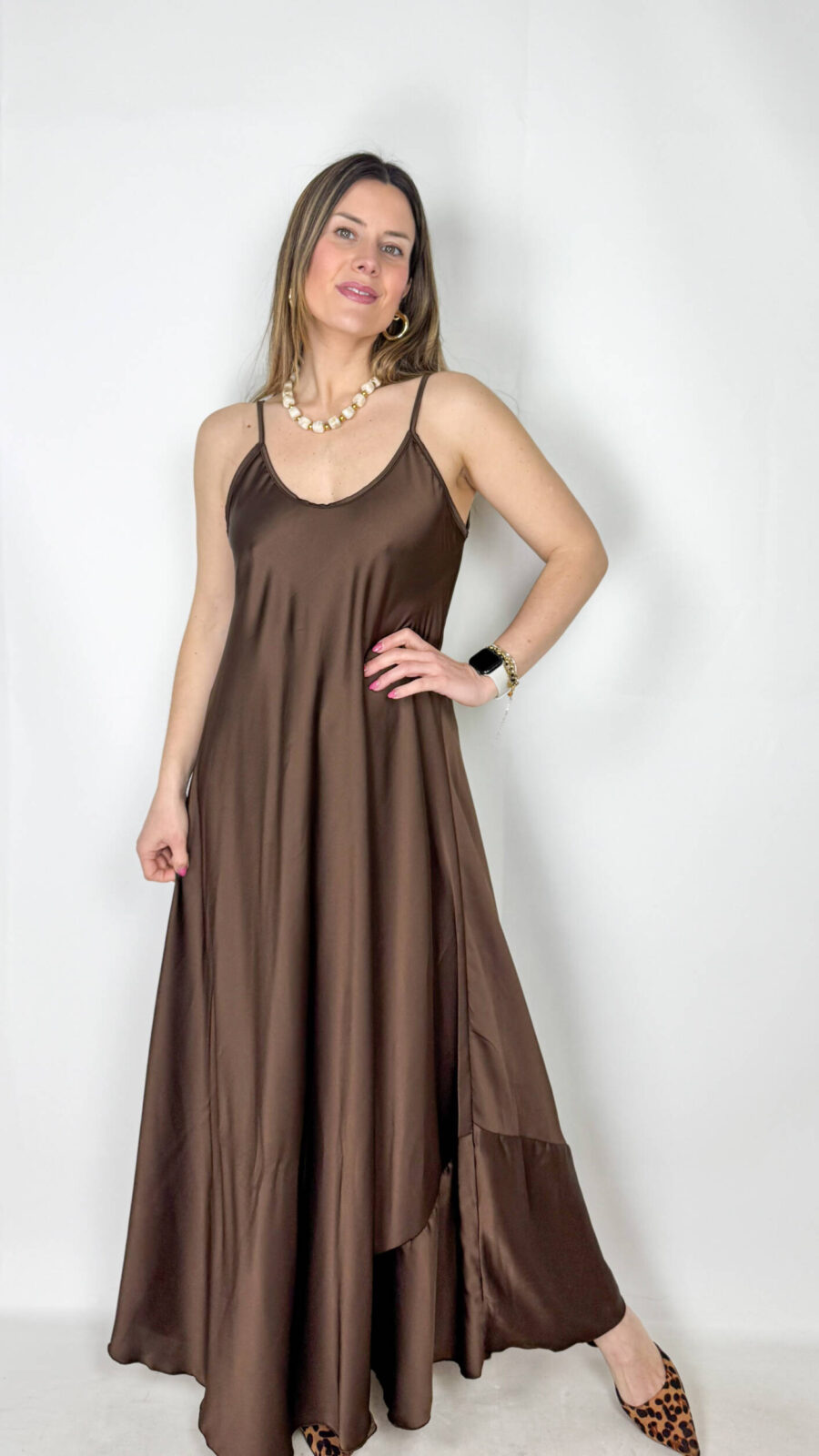 Abito dalla texture lucida, pensato per valorizzare la figura con eleganza essenziale e leggerezza. Le bretelle sottili e lo scollo a V sia sul davanti che sul retro donano un tocco femminile e raffinato, esaltando la linea del décolleté e della schiena. La vestibilità ampia e fluida accompagna il movimento del corpo con naturalezza, creando una caduta morbida e armoniosa