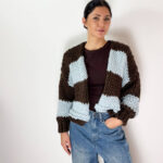 Aggiungi un tocco di stile unico e avvolgente al tuo guardaroba invernale con questo splendido cardigan oversized lavorato a maglia grossa. Caratterizzato da un design a grandi righe orizzontali a contrasto, accosta l'eleganza profonda del marrone cioccolato alla freschezza e delicatezza dell'azzurro cielo. Realizzato con una ricca miscela ad alto contenuto di lana, è il capo perfetto da indossare aperto per un look effortless chic, moderno e alla moda.
