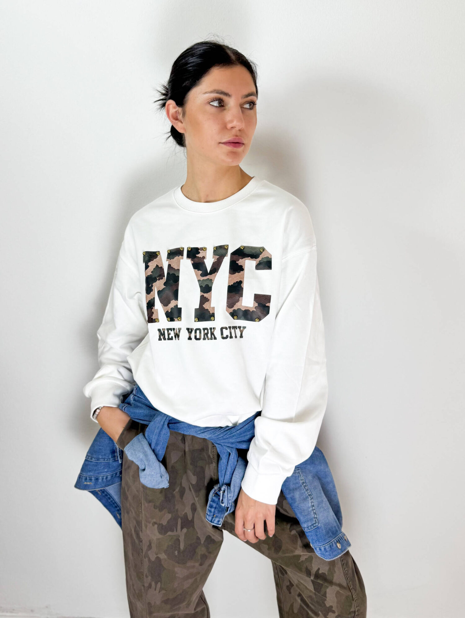 Aggiungi un tocco deciso e contemporaneo ai tuoi outfit con questa felpa girocollo in cotone garzato, morbida e confortevole, pensata per unire stile casual e carattere. Il modello presenta una vestibilità versatile e un interno in morbido cotone garzato, ideale per affrontare la stagione con comfort e praticità. Il dettaglio distintivo è la scritta frontale in fantasia camouflage, impreziosita da borchie decorative che donano alla felpa un look grintoso e originale. Perfetta da abbinare a jeans, pantaloni cargo o jogger, è un capo facile da indossare nel tempo libero e ideale per creare outfit urban e streetwear.