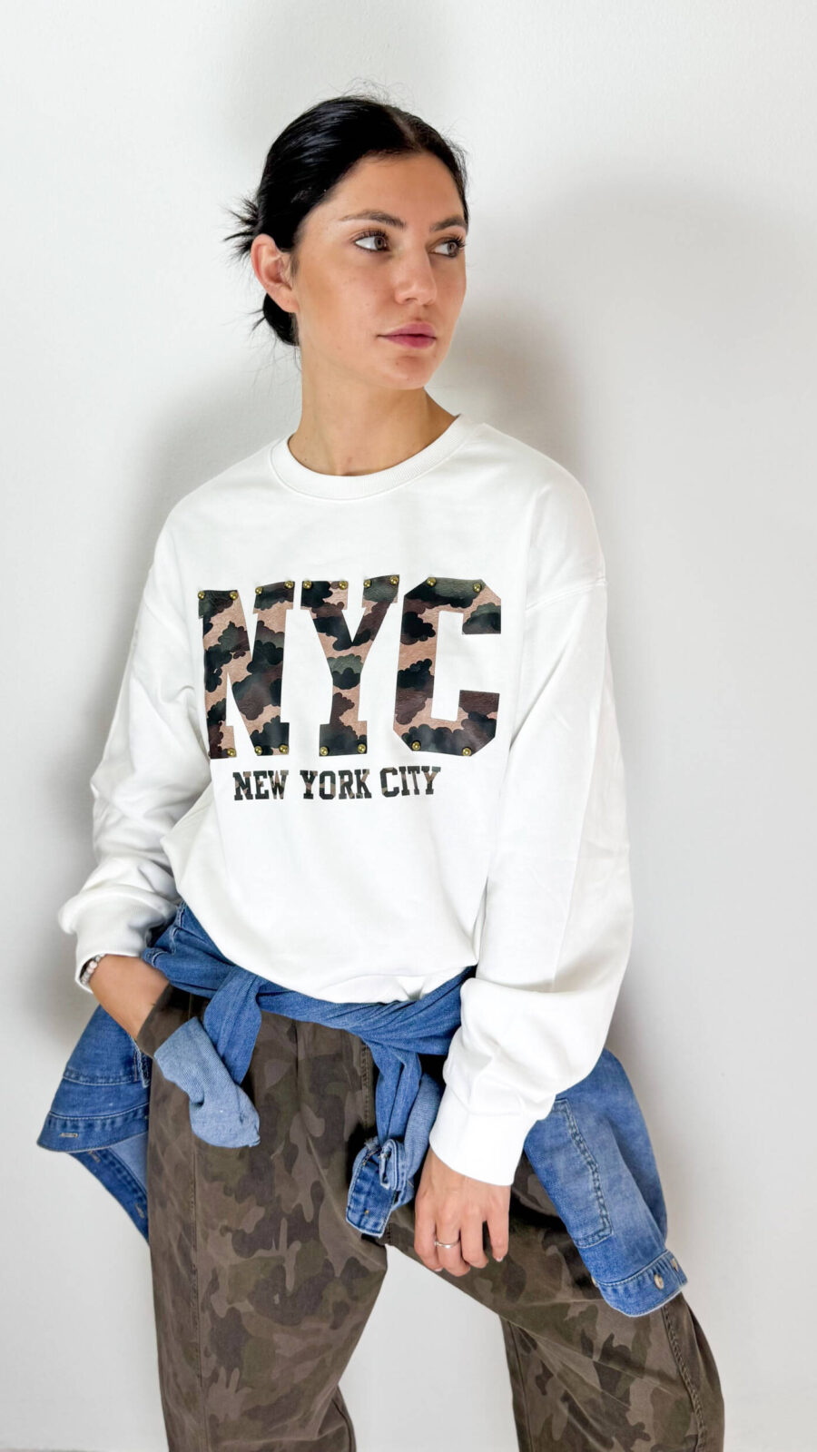 Aggiungi un tocco deciso e contemporaneo ai tuoi outfit con questa felpa girocollo in cotone garzato, morbida e confortevole, pensata per unire stile casual e carattere. Il modello presenta una vestibilità versatile e un interno in morbido cotone garzato, ideale per affrontare la stagione con comfort e praticità. Il dettaglio distintivo è la scritta frontale in fantasia camouflage, impreziosita da borchie decorative che donano alla felpa un look grintoso e originale. Perfetta da abbinare a jeans, pantaloni cargo o jogger, è un capo facile da indossare nel tempo libero e ideale per creare outfit urban e streetwear.