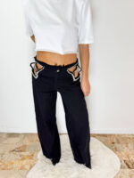 Jeans Maelle Black in denim lavaggio nero caratterizzato da dettagli cut-out con applicazioni di strass a stella. Fit morbido a palazzo e dettagli sfrangiati sul fondo. Taglia S: veste da una 36 a una 3