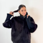 Unisci il lusso avvolgente dell'ecopelliccia alla praticità della maglieria con questa elegante giacca nera, ideale per affrontare le giornate più fredde con uno stile impeccabile. Realizzata con un pelo ecologico morbidissimo e denso, si caratterizza per gli originali ed eleganti inserti in maglia a coste lavorata sul collo alto e lungo le maniche. Il collo alto in maglia protegge dal vento donando un tocco sofisticato, mentre i polsini/maniche elasticizzate a coste assicurano massima aderenza e comfort vestibile. Dotata di una pratica chiusura frontale con zip integrata, è il capospalla perfetto da indossare sia su outfit serali e formali, sia sopra un look casual con jeans per un tocco glamour e contemporaneo.