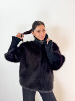 Unisci il lusso avvolgente dell'ecopelliccia alla praticità della maglieria con questa elegante giacca nera, ideale per affrontare le giornate più fredde con uno stile impeccabile. Realizzata con un pelo ecologico morbidissimo e denso, si caratterizza per gli originali ed eleganti inserti in maglia a coste lavorata sul collo alto e lungo le maniche. Il collo alto in maglia protegge dal vento donando un tocco sofisticato, mentre i polsini/maniche elasticizzate a coste assicurano massima aderenza e comfort vestibile. Dotata di una pratica chiusura frontale con zip integrata, è il capospalla perfetto da indossare sia su outfit serali e formali, sia sopra un look casual con jeans per un tocco glamour e contemporaneo.