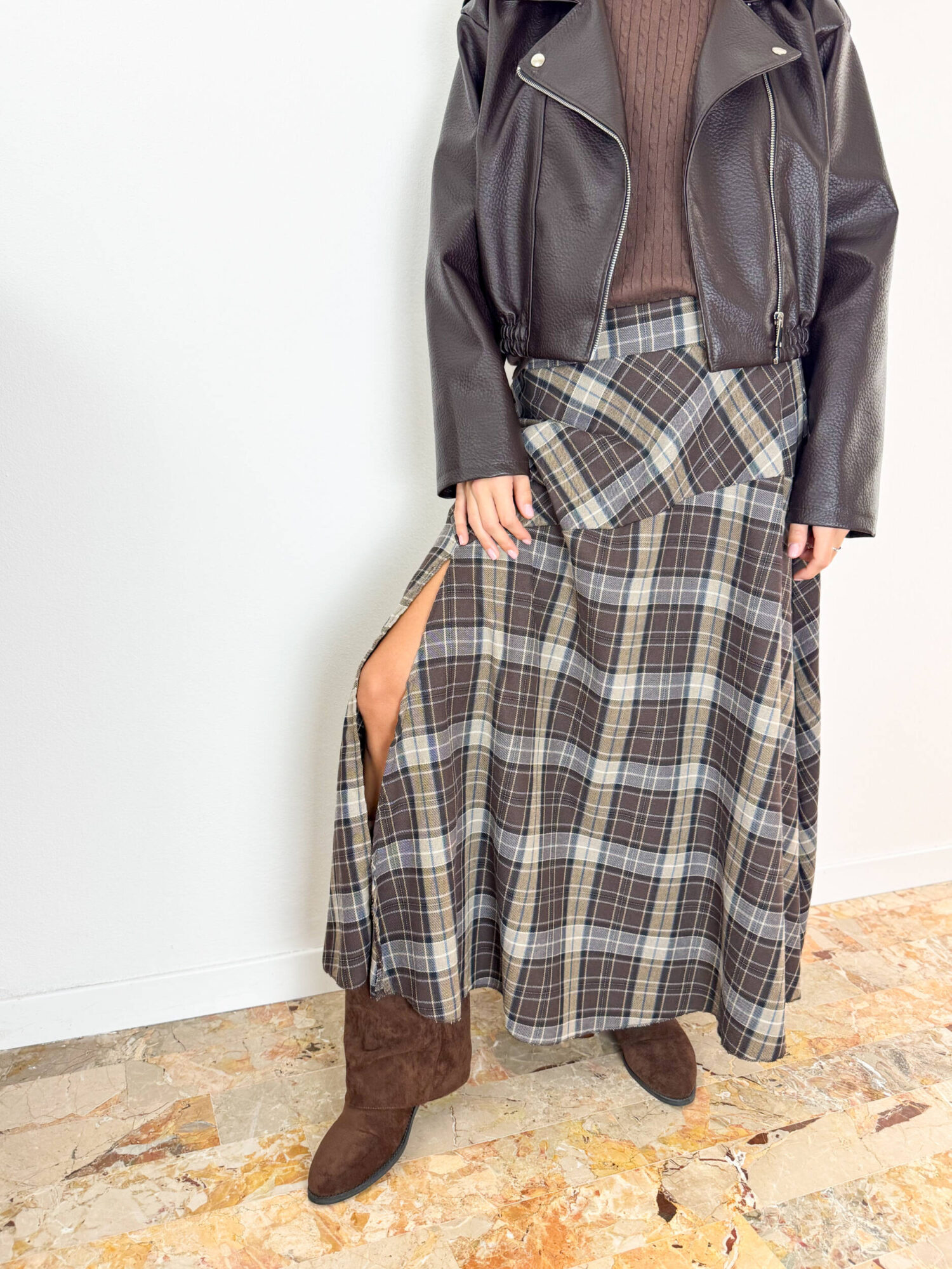 Aggiungi un tocco di carattere e raffinatezza al tuo stile autunno-inverno con questa gonna lunga dal classico e intramontabile motivo tartan a quadri sui toni del marrone, grigio e crema. Il design si distingue per il taglio dinamico con baschina/pannello asimmetrico sul davanti e un seducente spacco laterale che dona movimento e femminilità ad ogni passo. Progettata per garantire il massimo del comfort per tutto il giorno, è dotata di un pratico elastico in vita che assicura una vestibilità impeccabile e adattabile a diverse fisicità. Perfetta da abbinare a uno stivaletto in camoscio, un maglione avvolgente o una giacca in pelle per un look grintoso e di tendenza.