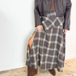 Aggiungi un tocco di carattere e raffinatezza al tuo stile autunno-inverno con questa gonna lunga dal classico e intramontabile motivo tartan a quadri sui toni del marrone, grigio e crema. Il design si distingue per il taglio dinamico con baschina/pannello asimmetrico sul davanti e un seducente spacco laterale che dona movimento e femminilità ad ogni passo. Progettata per garantire il massimo del comfort per tutto il giorno, è dotata di un pratico elastico in vita che assicura una vestibilità impeccabile e adattabile a diverse fisicità. Perfetta da abbinare a uno stivaletto in camoscio, un maglione avvolgente o una giacca in pelle per un look grintoso e di tendenza.
