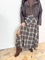 Aggiungi un tocco di carattere e raffinatezza al tuo stile autunno-inverno con questa gonna lunga dal classico e intramontabile motivo tartan a quadri sui toni del marrone, grigio e crema. Il design si distingue per il taglio dinamico con baschina/pannello asimmetrico sul davanti e un seducente spacco laterale che dona movimento e femminilità ad ogni passo. Progettata per garantire il massimo del comfort per tutto il giorno, è dotata di un pratico elastico in vita che assicura una vestibilità impeccabile e adattabile a diverse fisicità. Perfetta da abbinare a uno stivaletto in camoscio, un maglione avvolgente o una giacca in pelle per un look grintoso e di tendenza.