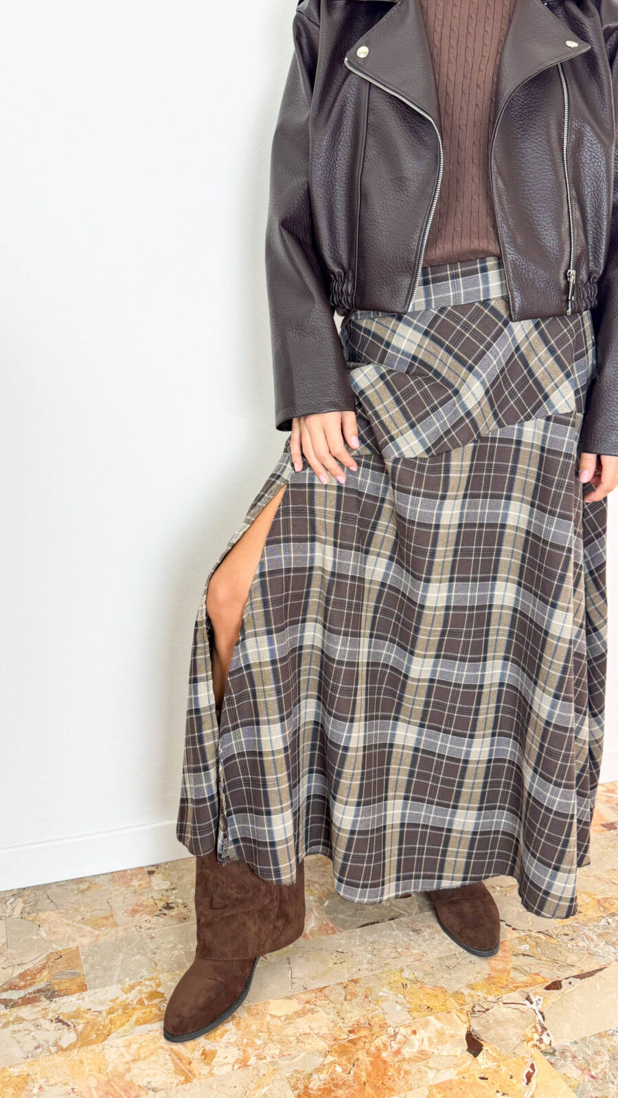 Aggiungi un tocco di carattere e raffinatezza al tuo stile autunno-inverno con questa gonna lunga dal classico e intramontabile motivo tartan a quadri sui toni del marrone, grigio e crema. Il design si distingue per il taglio dinamico con baschina/pannello asimmetrico sul davanti e un seducente spacco laterale che dona movimento e femminilità ad ogni passo. Progettata per garantire il massimo del comfort per tutto il giorno, è dotata di un pratico elastico in vita che assicura una vestibilità impeccabile e adattabile a diverse fisicità. Perfetta da abbinare a uno stivaletto in camoscio, un maglione avvolgente o una giacca in pelle per un look grintoso e di tendenza.