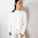 Vivi la stagione fredda nell'abbraccio del comfort assoluto con questo raffinato coordinato in calda maglia bianca. Realizzato in un tessuto morbidissimo ed altamente elasticizzato, questo set due pezzi unisce eleganza, praticità e una vestibilità avvolgente che si adatta delicatamente ad ogni silhouette. La sua eccezionale elasticità e morbidezza lo rendono un capo ideale e super confortevole anche durante il periodo della gravidanza. Il completo è composto da una maglia a girocollo con maniche lunghe dal taglio scivolato e da un pantalone morbido abbinato. Estremamente versatile, è perfetto sia indossato come total look per un outfit loungewear di classe, sia da spezzare e combinare separatamente: abbinando la maglia ai tuoi jeans preferiti o il pantalone a una maxi felpa. Un indumento essenziale per viaggiare, rilassarsi o per i tuoi look tutti i giorni.
