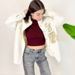 Aggiungi un tocco unico e di carattere al tuo guardaroba invernale con questa giacca oversize in velluto a costine. Realizzata in un luminoso ed elegante colore panna/bianco, unisce il calore del velluto a un design scenografico e di tendenza. Il vero punto di forza è il retro, impreziosito da dettagli intrecciati e lunghe frange sulla schiena in stile boho-chic. Fit & Design: Vestibilità oversize e rilassata, ideale per creare outfit a strati sopra maglioni pesanti durante la stagione fredda. Dettagli Glamour: Dettaglio posteriore effetto macramè/uncinetto con frange pendenti che donano movimento a ogni passo. Materiale: morbido e avvolgente velluto a costine, perfetto per proteggerti dal freddo invernale con stile. Come Abbinarla: Splendida sopra un denim grigio o nero, stivaletti o anfibi per un perfetto look street-style western e ricercato