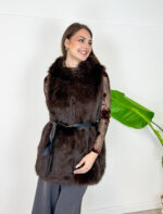 Aggiungi un tocco di raffinatezza e calore ai tuoi outfit invernali con questo gilet smanicato in ecopelliccia marrone scuro. Un capo morbido, avvolgente ed estremamente versatile, ideale per affrontare le giornate più fredde con stile. Dotato di un pratico cappuccio integrato e completamente foderato internamente, garantisce massimo comfort e protezione dal vento. Design e Silhouette: Taglio medio-lungo valorizzato da una cintura nera in vita che definisce la figura regalando una linea elegante e femminile. Dettagli Funzionali: Ampio cappuccio foderato e finitura in eco-pelliccia sintetica ad alta densità, morbida al tatto e dal look lussuoso. Come Abbinarlo: Perfetto indossato sopra una maglia a maniche lunghe, un dolcevita o una camicia trasparente per le serate speciali, abbinato a pantaloni a gamba larga o gonne midi.