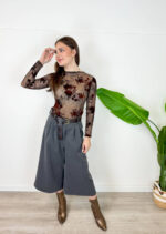 Aggiungi eleganza e modernità al tuo guardaroba con questi sofisticati pantaloni culotte colore grigio antracite/scuro. Caratterizzati da un taglio cropped a gamba molto ampia, offrono la combinazione perfetta tra la raffinatezza di una gonna e la praticità di un pantalone palazzo. Design e Dettagli: Struttura a vita alta impreziosita da eleganti pinces frontali che creano un bellissimo movimento e da una cintura coordinata in stoffa che segna e valorizza il punto vita. Vestibilità e Comfort: Gamba larga e fluida che cade morbida a metà polpaccio, garantendo massima libertà di movimento e una silhouette slanciata. Come Abbinarli: Perfetti da indossare con stivaletti o tronchetti in pelle, un body aderente o un maglioncino inserito all'interno per un look da ufficio impeccabile o un outfit serale chic ed eclettico.