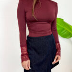 Esalta la tua silhouette con questo raffinato body a lupetto colore bordeaux/burgundy, pensato per chi cerca eleganza e stile in un unico capo. Caratterizzato da spalline strutturate con leggera imbottitura che valorizzano la figura e da romantici polsini in pizzo lavorato in tinta, è perfetto per donare un touch chic a ogni outfit. Design e Fit: Vestibilità aderente, collo alto a lupetto e linea pulita che rimane sempre impeccabile all'interno di gonne e pantaloni. Dettagli Glamour: Polsi rifiniti in pizzo floreale e spalle definite per un look moderno e grintoso. Come Indossarlo: Ideale abbinato a minigonne in velluto, pantaloni a vita alta o sotto una giacca blazer per occasioni serali o un look da ufficio ricercato.