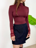 Esalta la tua silhouette con questo raffinato body a lupetto colore bordeaux/burgundy, pensato per chi cerca eleganza e stile in un unico capo. Caratterizzato da spalline strutturate con leggera imbottitura che valorizzano la figura e da romantici polsini in pizzo lavorato in tinta, è perfetto per donare un touch chic a ogni outfit. Design e Fit: Vestibilità aderente, collo alto a lupetto e linea pulita che rimane sempre impeccabile all'interno di gonne e pantaloni. Dettagli Glamour: Polsi rifiniti in pizzo floreale e spalle definite per un look moderno e grintoso. Come Indossarlo: Ideale abbinato a minigonne in velluto, pantaloni a vita alta o sotto una giacca blazer per occasioni serali o un look da ufficio ricercato.